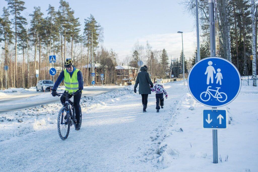 Pyöräilijä lumisella kadulla
